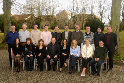 Un groupe d'adultes posant en extérieur sur une pelouse verte, avec un arbre en arrière-plan.