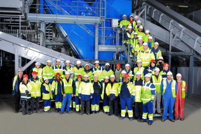Un groupe d'adultes posant en extérieur sur une pelouse verte, avec un arbre en arrière-plan.