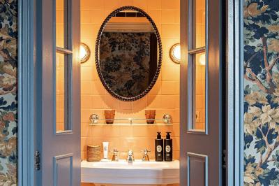 Salle de bain luxueuse avec un plan de travail en marbre vert, miroir encadré, produits de toilette et éclairage mural.