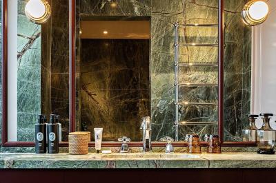 Salle de bain luxueuse avec un plan de travail en marbre vert, miroir encadré, produits de toilette et éclairage mural.