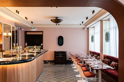 Salle de bain luxueuse avec un plan de travail en marbre vert, miroir encadré, produits de toilette et éclairage mural.