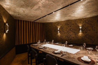 Salle de bain luxueuse avec un plan de travail en marbre vert, miroir encadré, produits de toilette et éclairage mural.