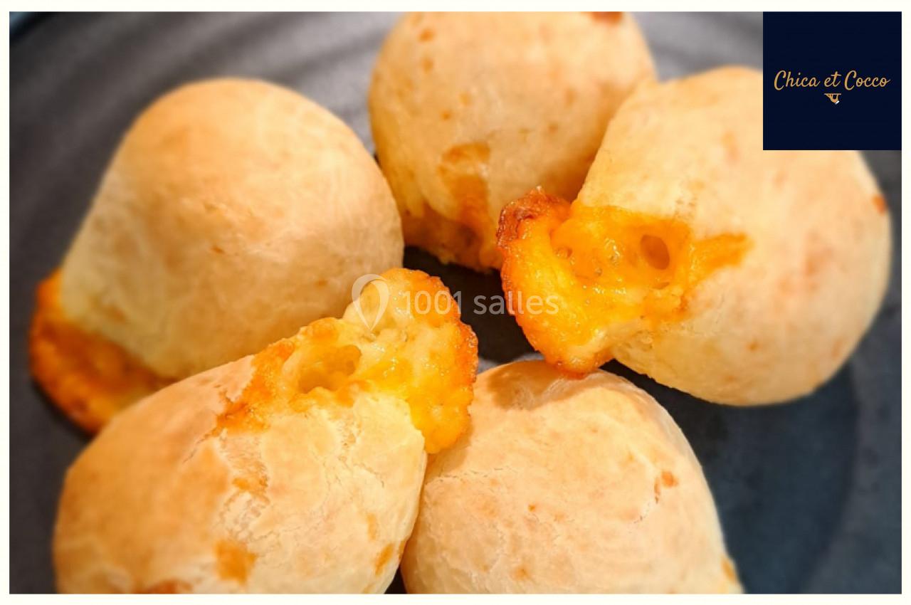 Quatre petits pains dorés au fromage, disposés sur une assiette sombre.