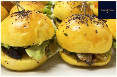 Assiette de beignets dorés disposés en cercle sur une table, avec un serveur en arrière-plan.
