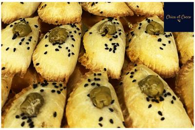 Assiette de beignets dorés disposés en cercle sur une table, avec un serveur en arrière-plan.