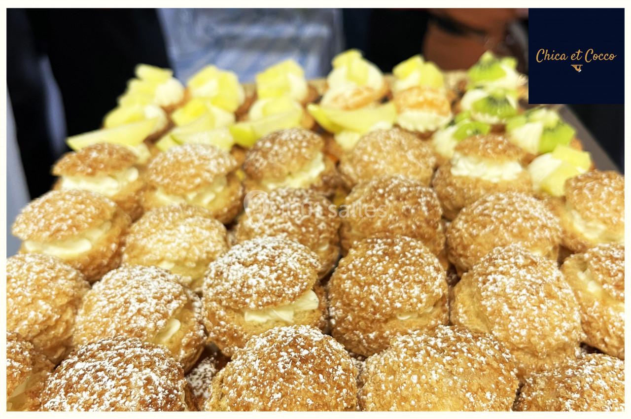 Plateau de choux pâtissiers dorés, garnis de crème et saupoudrés de sucre glace, accompagnés de morceaux de citron.