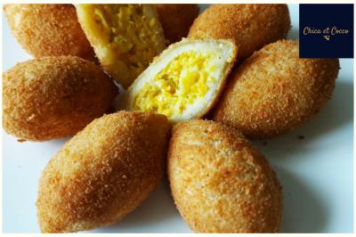 Assiette de beignets dorés disposés en cercle sur une table, avec un serveur en arrière-plan.