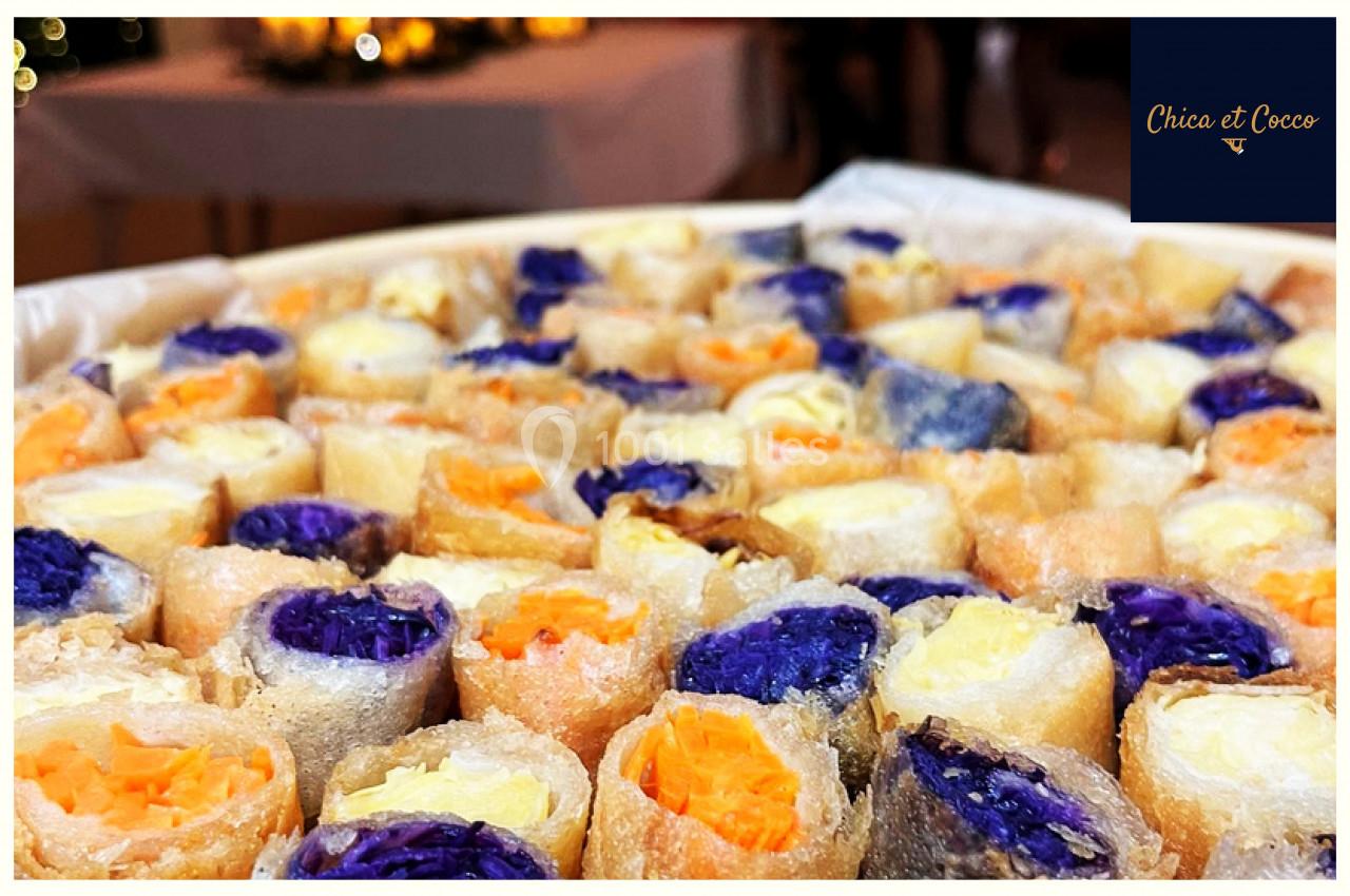 Assortiment de rouleaux de printemps colorés garnis de légumes orange, violet et blanc, présentés sur un plateau.