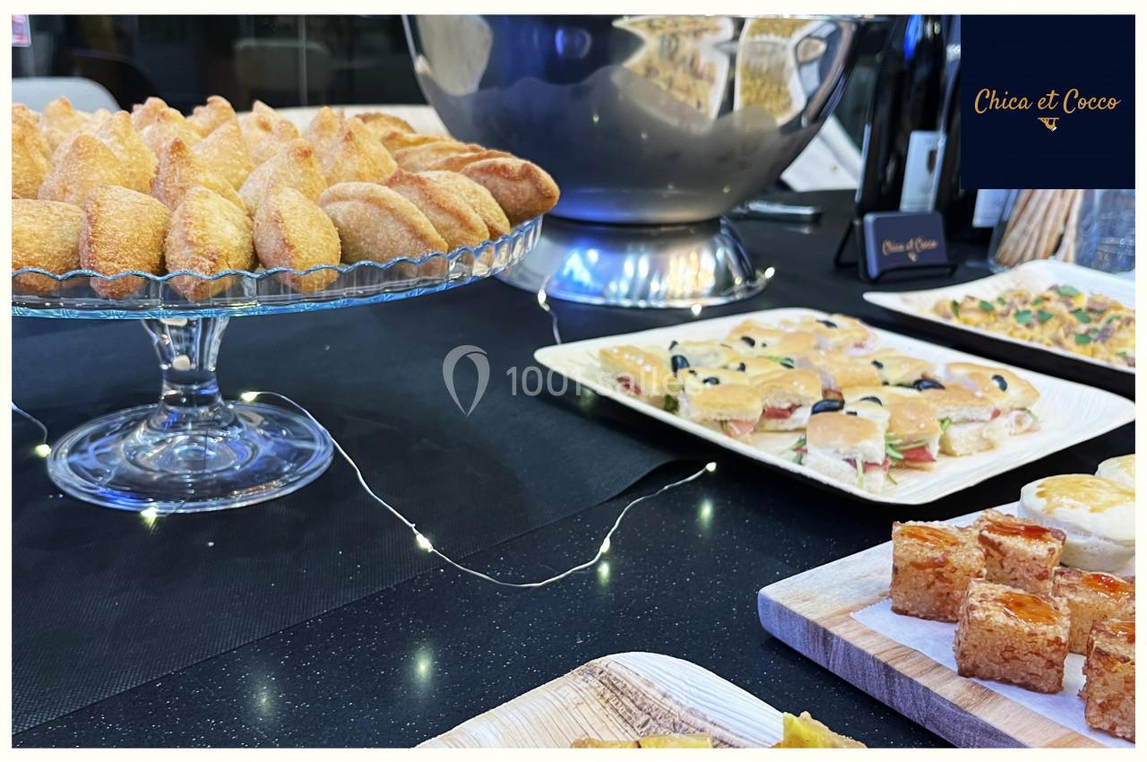 Plateau de pâtisseries et amuse-bouches variés disposés sur une table noire avec une décoration lumineuse.