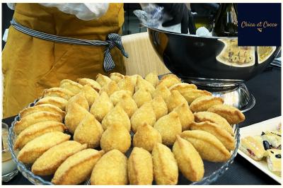 Assiette de beignets dorés disposés en cercle sur une table, avec un serveur en arrière-plan.