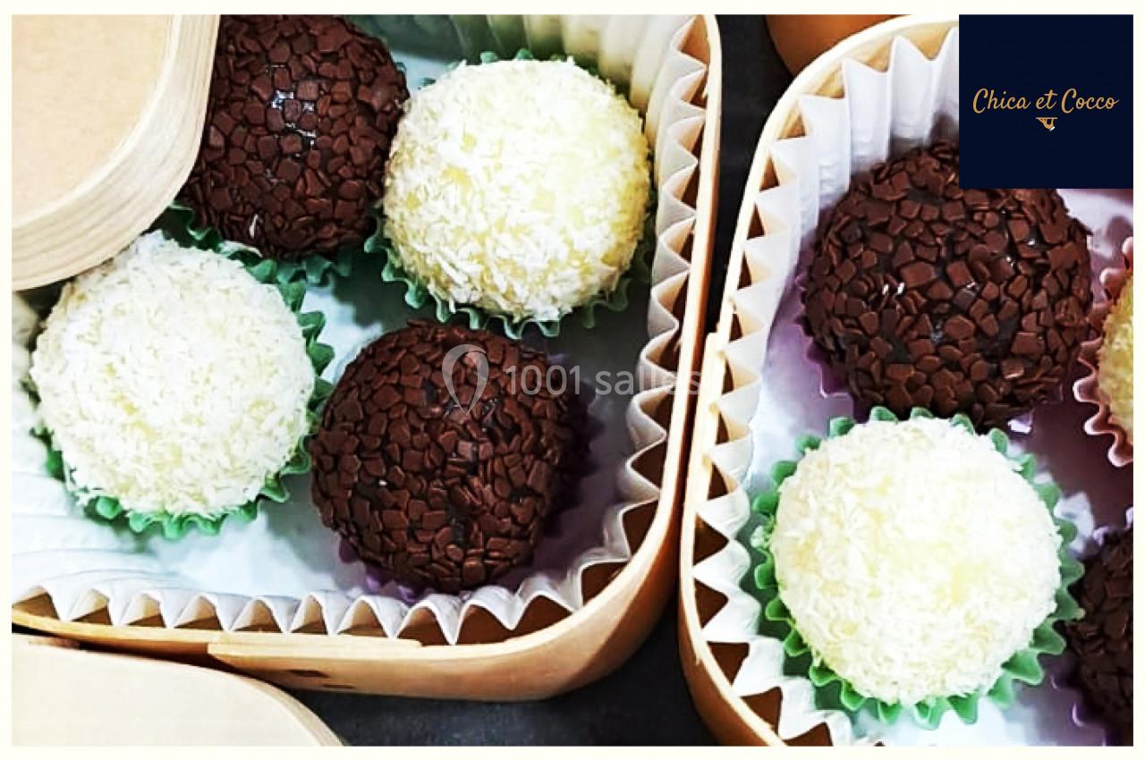 Assortiment de truffes au chocolat noir et blanc présentées dans des boîtes en carton avec caissettes colorées.