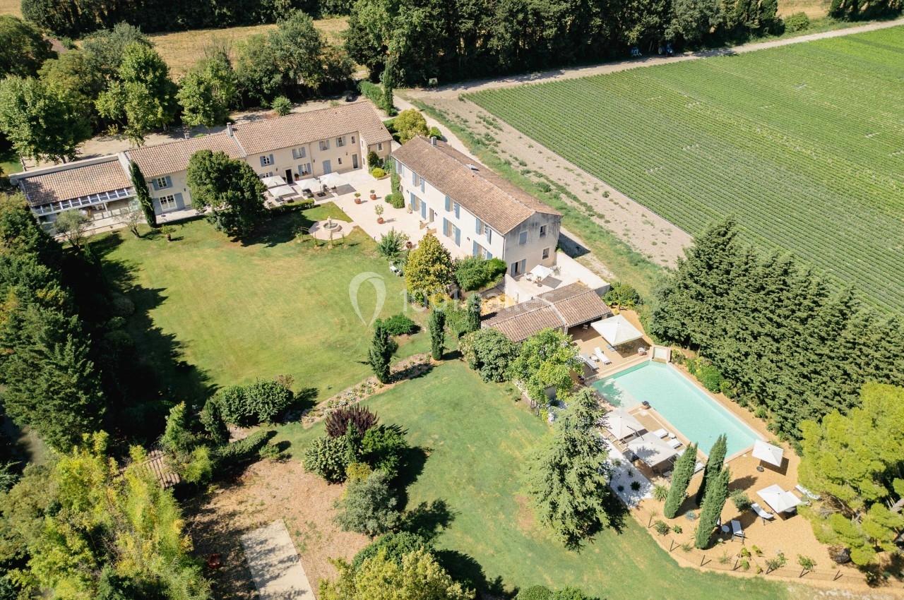 Vue aérienne d'une propriété avec plusieurs bâtiments, un grand jardin, une piscine et des champs environnants.