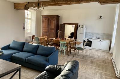 Miniature Au sein des gîtes : le grand salon Ruines éclairées et bâtiment adjacent sous un ciel nocturne, avec un arbre illuminé et des bancs sur une pelouse.