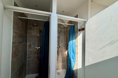 Miniature Au sein des gîtes : les salles d'eau Ruines éclairées et bâtiment adjacent sous un ciel nocturne, avec un arbre illuminé et des bancs sur une pelouse.