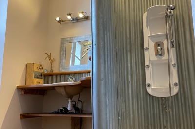 Miniature Au sein des gîtes : les salles d'eau Ruines éclairées et bâtiment adjacent sous un ciel nocturne, avec un arbre illuminé et des bancs sur une pelouse.