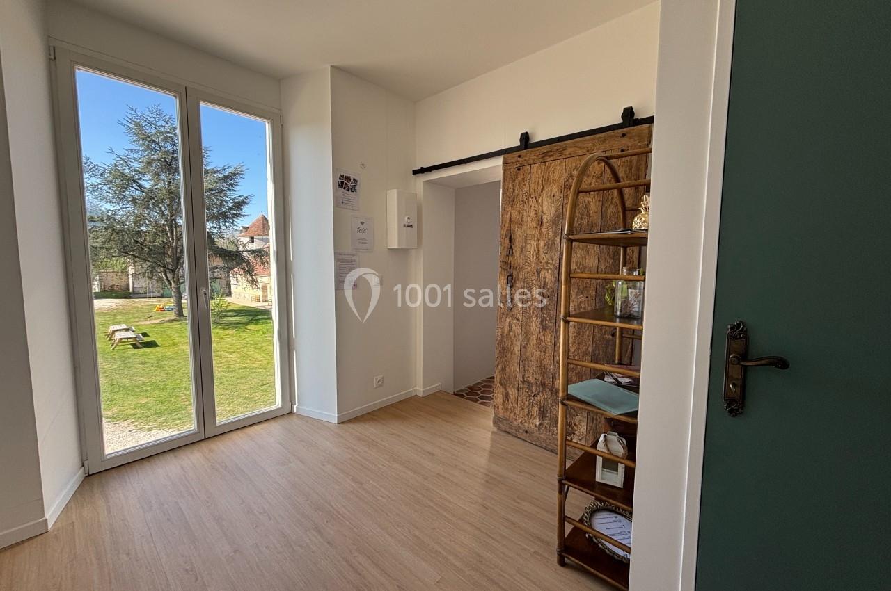 Vue d'une pièce lumineuse avec parquet, porte coulissante en bois, étagère et grande baie vitrée donnant sur un jardin.