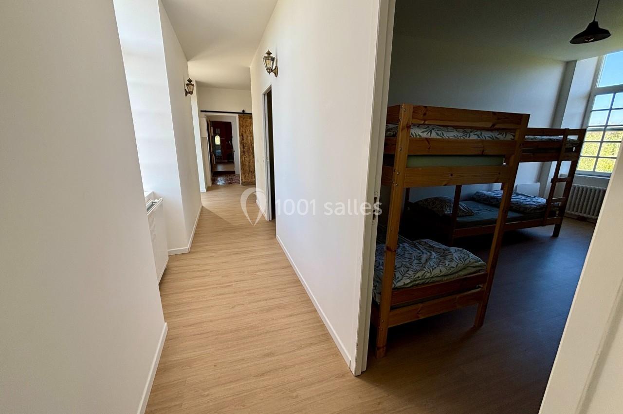 Vue d'un couloir lumineux menant à une chambre avec lits superposés en bois, éclairée par une grande fenêtre.