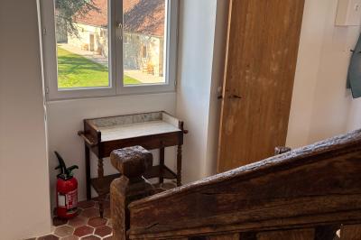 Miniature Au sein des gîtes : lieu de passage Ruines éclairées et bâtiment adjacent sous un ciel nocturne, avec un arbre illuminé et des bancs sur une pelouse.