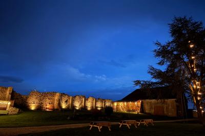Miniature La cour de nuit Ruines éclairées et bâtiment adjacent sous un ciel nocturne, avec un arbre illuminé et des bancs sur une pelouse.