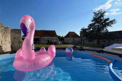 Miniature La piscine chauffée en été Ruines éclairées et bâtiment adjacent sous un ciel nocturne, avec un arbre illuminé et des bancs sur une pelouse.
