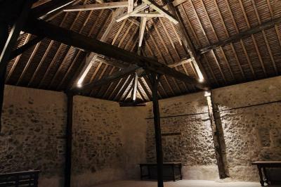 Miniature Le préau de nuit Ruines éclairées et bâtiment adjacent sous un ciel nocturne, avec un arbre illuminé et des bancs sur une pelouse.