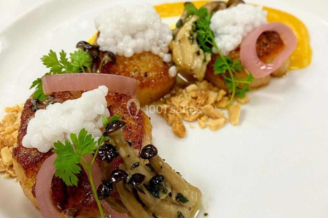Assiette gastronomique avec noix de Saint-Jacques, champignons, pickles d'oignon, perles blanches et herbes fraîches.