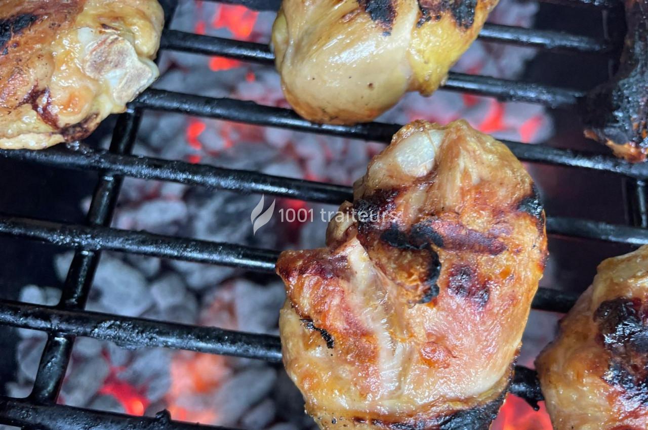 Morceaux de viande grillés sur un barbecue avec des braises incandescentes en arrière-plan.