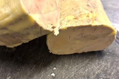 Miniature Traiteur Navarrenx (Pyrénées-Atlantiques) - Maison K Traiteur Event #51 Bloc de préparation alimentaire enrobé d'une couche jaune, posé sur une planche noire sur une surface métallique.