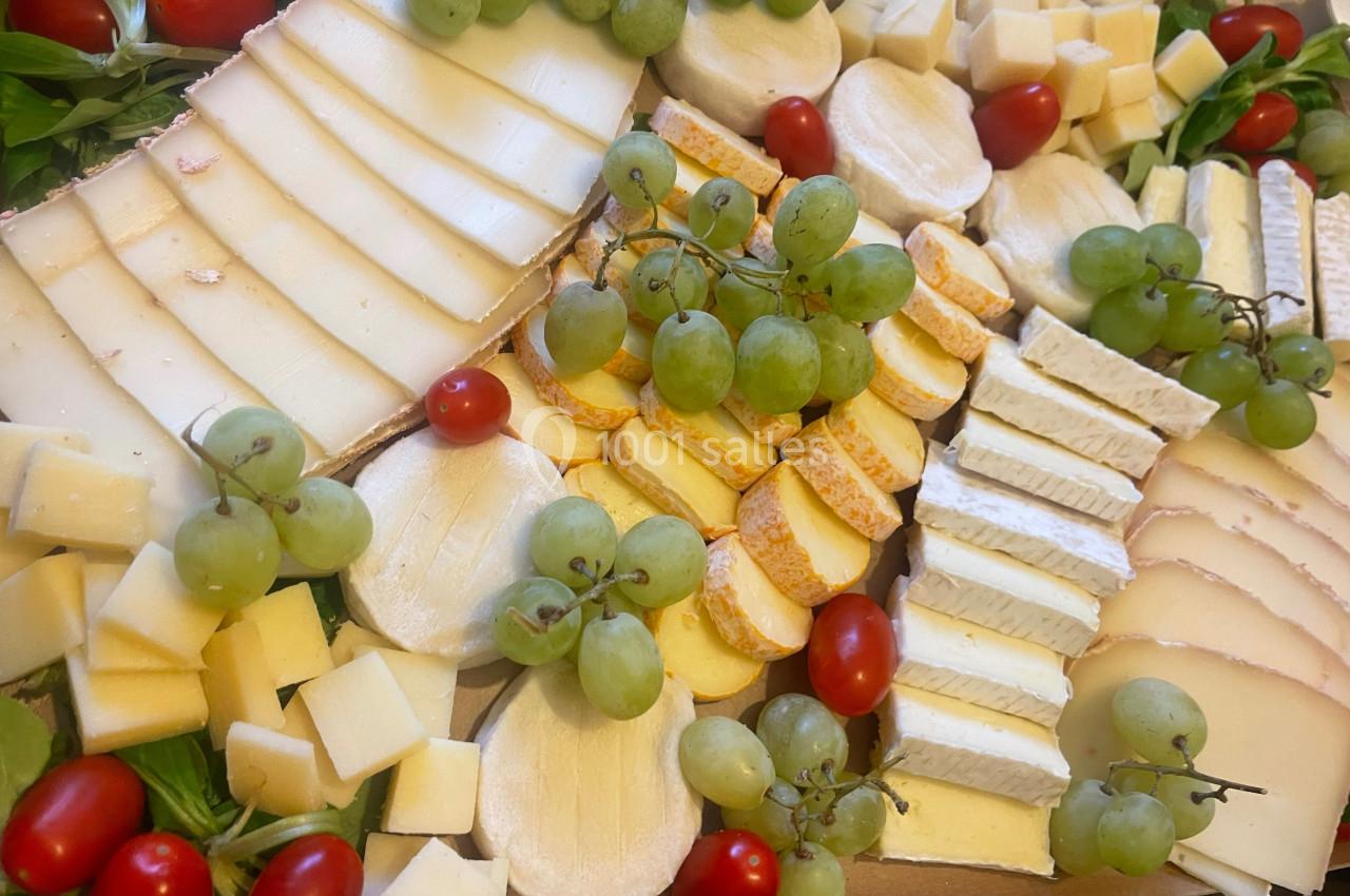 Plateau de fromages variés avec raisins verts, tomates cerises et tranches de différents types de fromages.