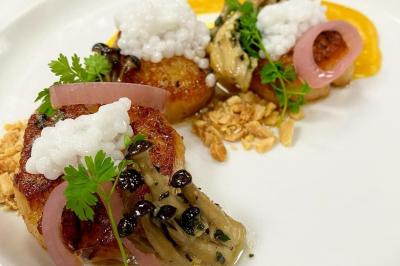 Assiettes composées de steaks grillés, purée, groseilles rouges, salade verte garnie de fleurs comestibles et sauce.