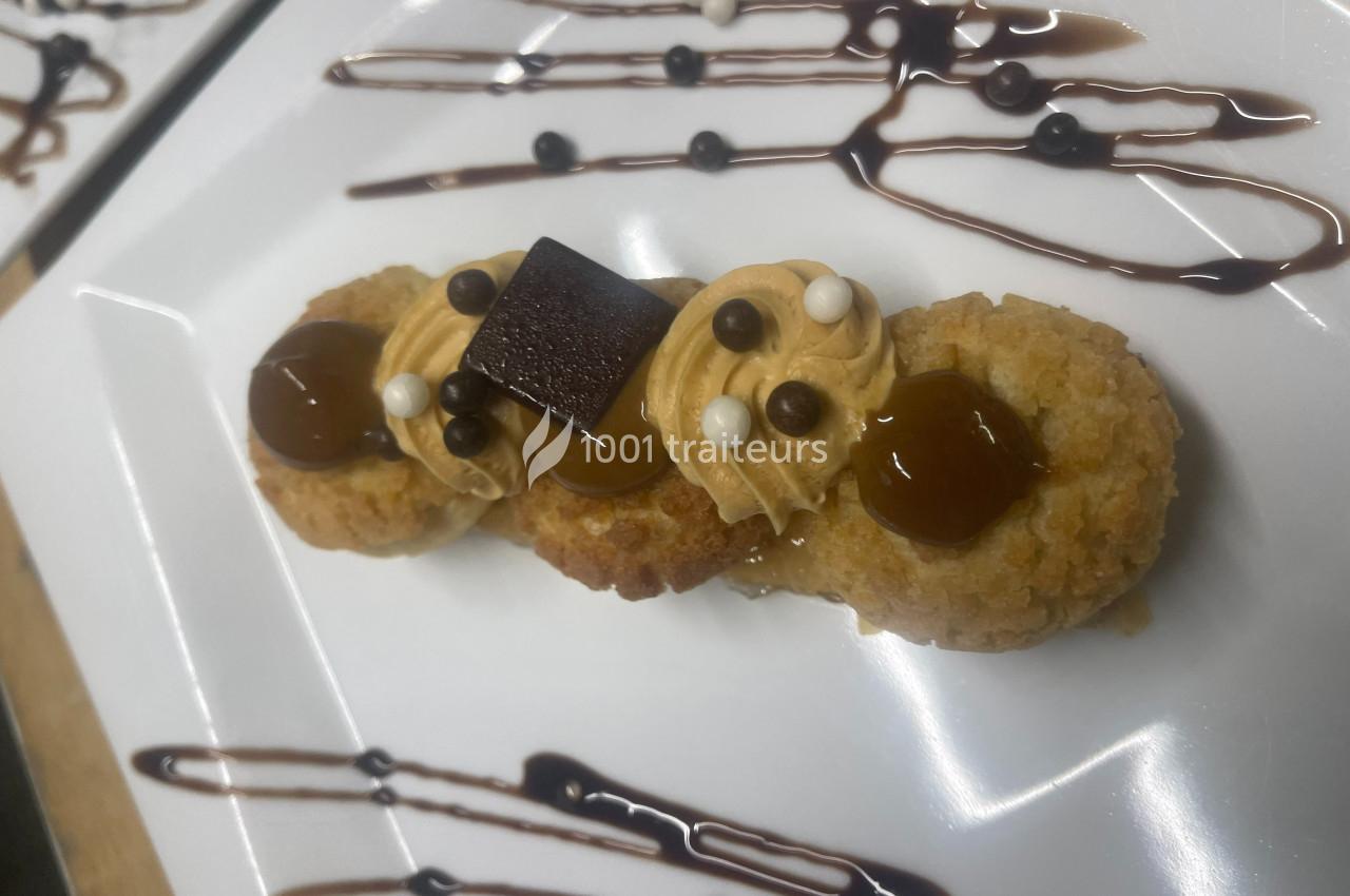 Dessert composé de petits gâteaux garnis de crème, caramel, perles croustillantes et décoré de traits de sauce chocolat.