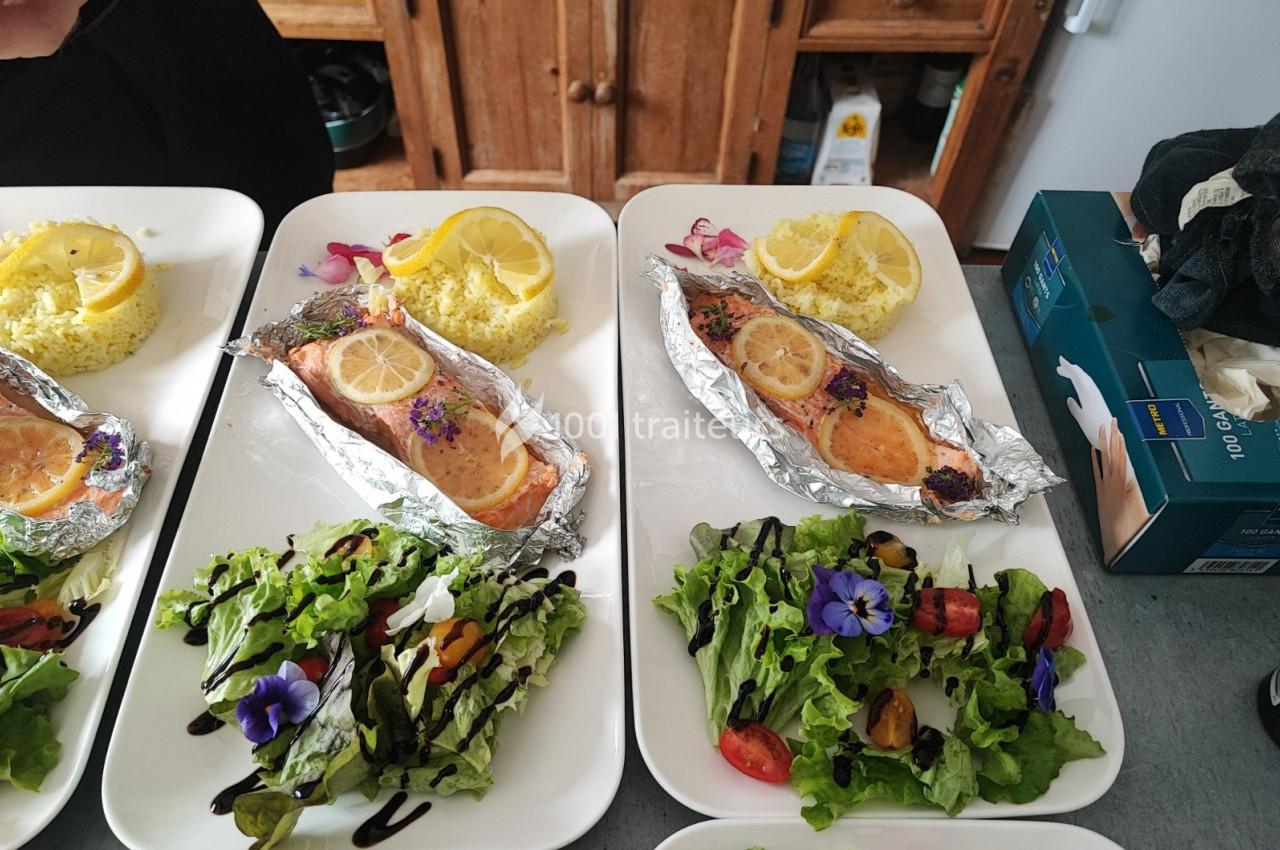 Assiettes composées de saumon en papillote avec rondelles de citron, salade garnie et riz accompagné de citron.