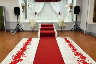 Table décorée avec des flûtes en verre, un bouquet de fleurs blanches, une bougie et des fauteuils ornés en arrière-plan.