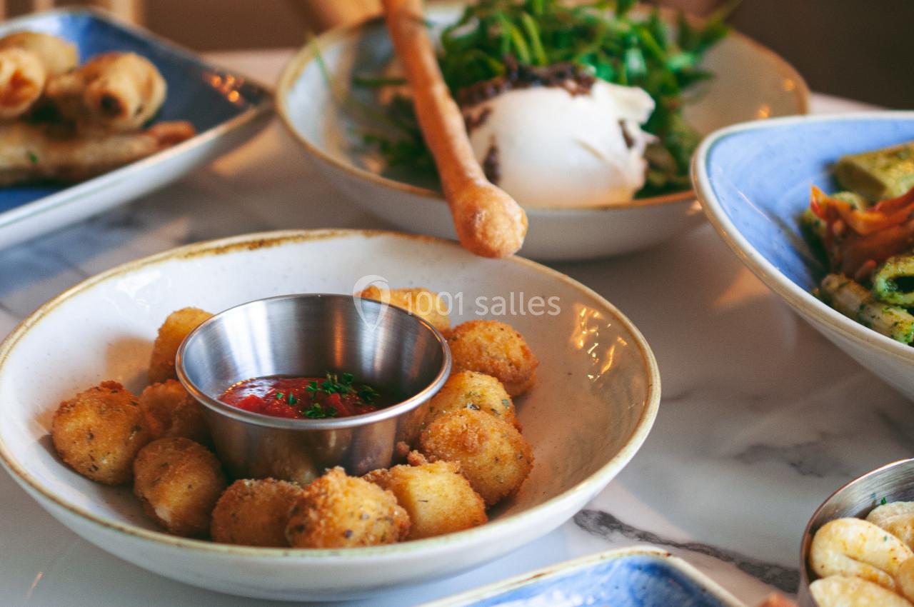 Assortiment de plats italiens sur une table, incluant burrata, charcuterie, croquettes et légumes grillés.