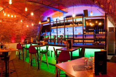 Salle de restaurant lumineuse avec banquettes bleues, chaises colorées, décor végétal et éclairage chaleureux.