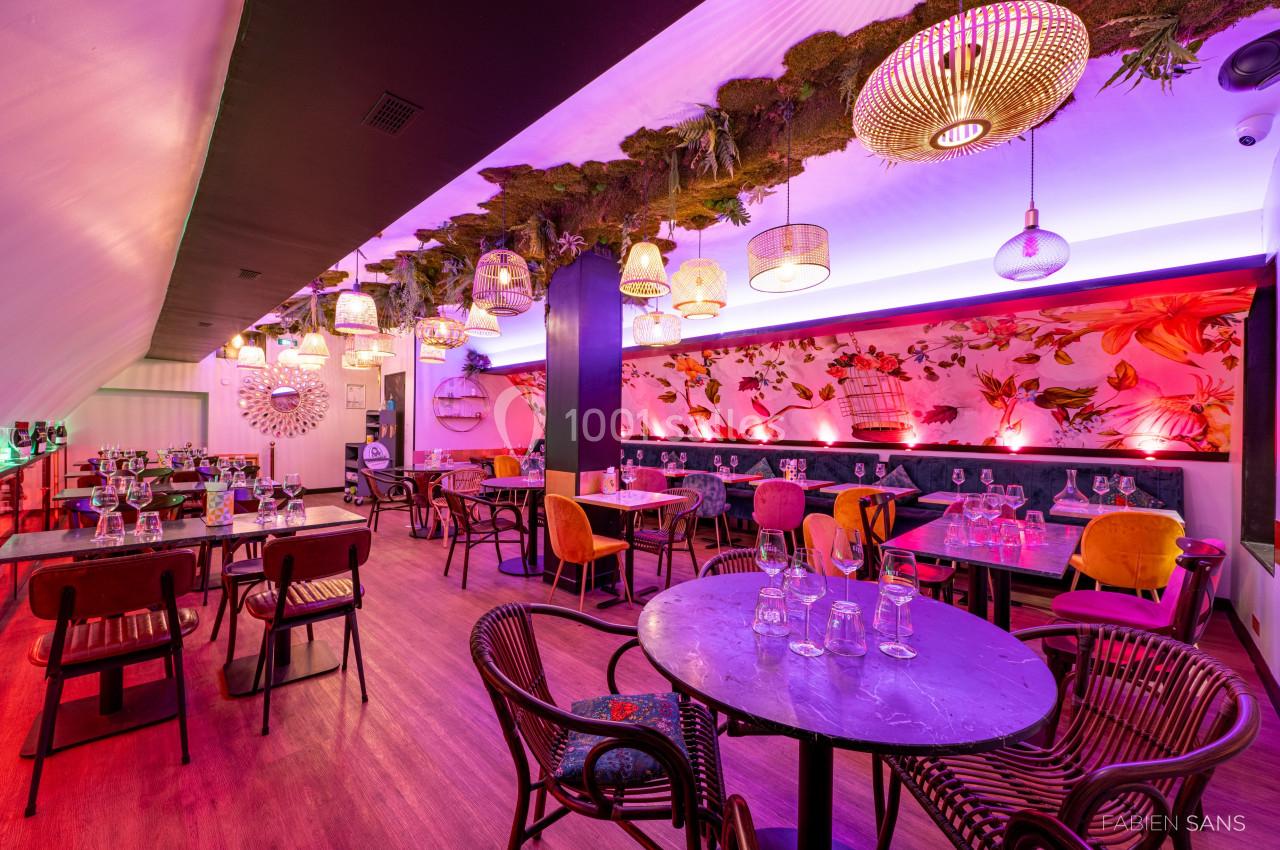 Salle de restaurant colorée avec décoration florale, mobilier éclectique et éclairage tamisé.