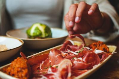 Salle de restaurant lumineuse avec banquettes bleues, chaises colorées, décor végétal et éclairage chaleureux.