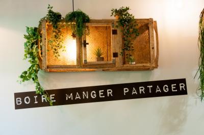 Salle de restaurant lumineuse avec banquettes bleues, chaises colorées, décor végétal et éclairage chaleureux.