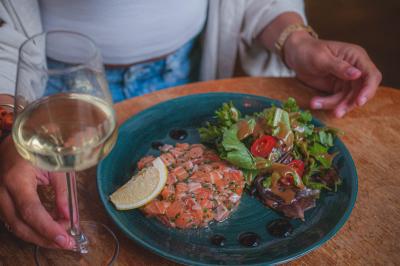 Salle de restaurant lumineuse avec banquettes bleues, chaises colorées, décor végétal et éclairage chaleureux.