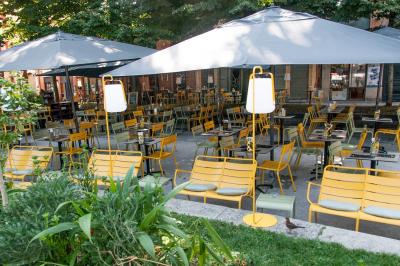 Salle de restaurant lumineuse avec banquettes bleues, chaises colorées, décor végétal et éclairage chaleureux.