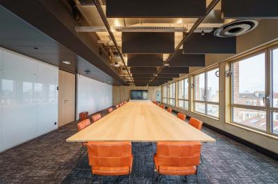 Bâtiment moderne en briques avec de grandes fenêtres, entouré de végétation et de parasols jaunes au premier plan.