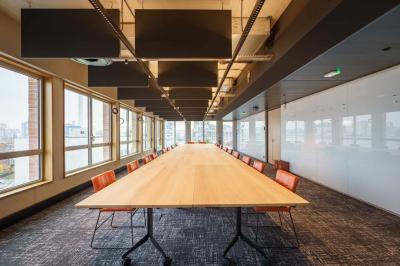 Bâtiment moderne en briques avec de grandes fenêtres, entouré de végétation et de parasols jaunes au premier plan.