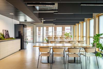 Bâtiment moderne en briques avec de grandes fenêtres, entouré de végétation et de parasols jaunes au premier plan.