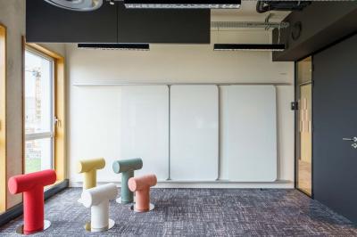 Bâtiment moderne en briques avec de grandes fenêtres, entouré de végétation et de parasols jaunes au premier plan.