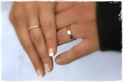 Miniature Cédric Chapelon Photographe #4 Femme en robe de mariée blanche tenant un bouquet de fleurs blanches et décorations bleues, en extérieur sur pelouse.