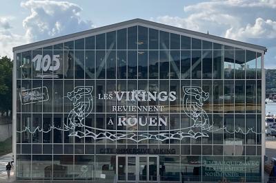 Une danseuse en tenue noire effectue une pose gracieuse sur une scène éclairée, devant un public attentif.