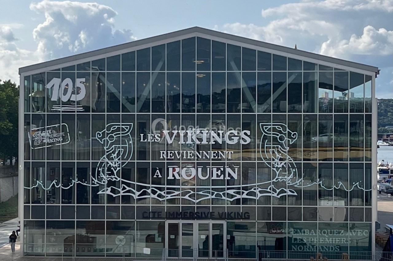 Façade vitrée d'un bâtiment avec l'inscription ’Les Vikings reviennent à Rouen’ et des motifs nordiques.