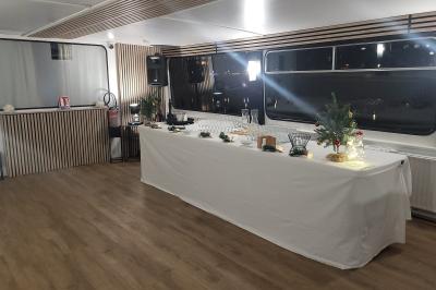 Salle de réception sur un bateau avec tables recouvertes de nappes blanches et plancher en bois clair.
