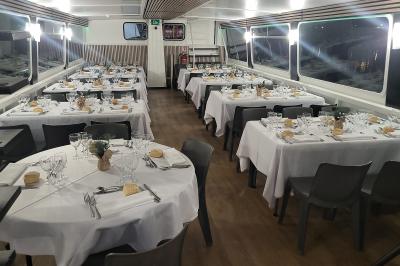 Salle de réception sur un bateau avec tables recouvertes de nappes blanches et plancher en bois clair.
