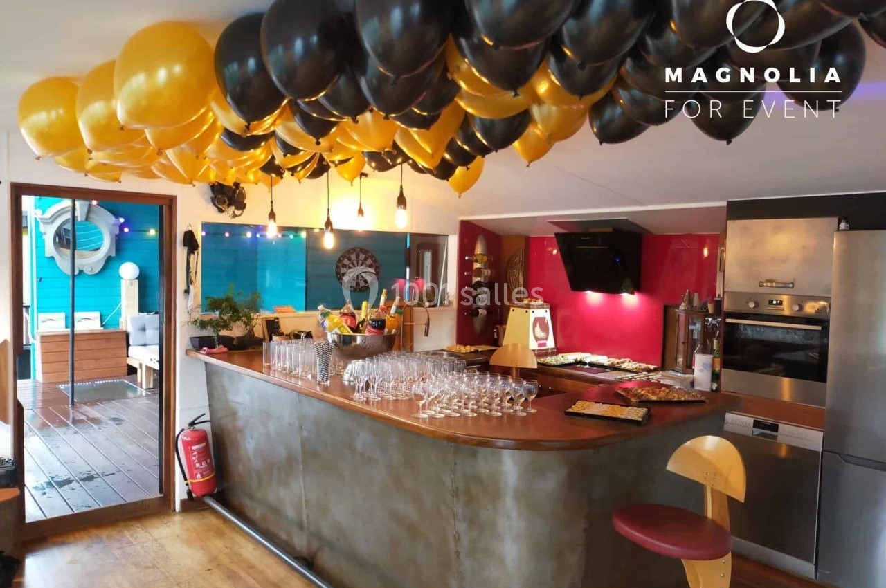 Ballons noirs et jaunes décorant un bar intérieur avec des verres alignés et un buffet en arrière-plan.